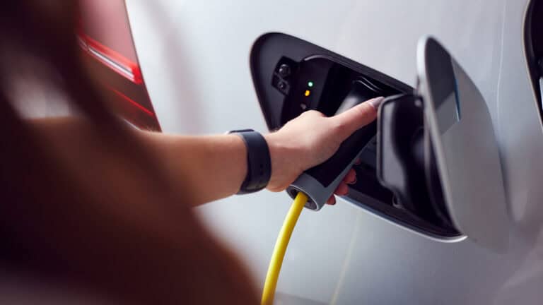 Close Up Of Hand Attaching Power Cable To Environmentally Friendly Zero Emission Electric Car